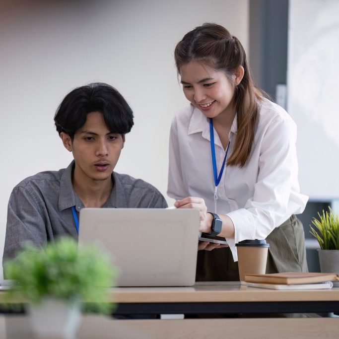 A business team analyzing data and discuss strategy in a modern office setting with laptops and coffee.
