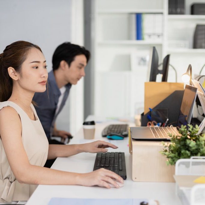 Young asian businesswoman using laptop at office table. company employees sitting at work, Accounting staff working towards marketing.